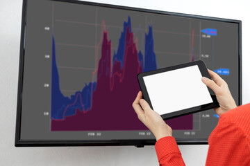 Woman holding pc tablet with white blank screen against big screen and graphs image.Concept of...