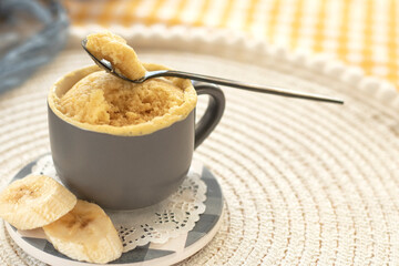 cupcake in a mug with banana pieces. Banana cupcake on a light background. vanilla biscuit in a...