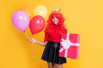 glad child in crown with present box and party balloon on yellow background