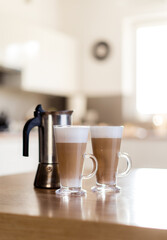 Two latte macchiato coffee in the glass with milk foam on wooden table, moka pot, home made.
