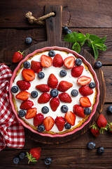 Fototapeta na wymiar Delicious strawberry pie with fresh blueberry and whipped cream on wooden rustic table, cheesecake, top view