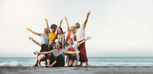 Best friends having fun together at the beach - Group of happy young people with arms up enjoying...