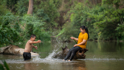 Happy Country Boy And Girl smiling Playing Water at the River in asian.