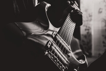 A young man wipes dust off an electric guitar. close-up. Sun rays. black and white