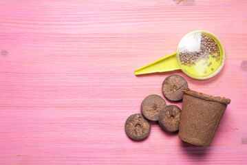 Gardening concept background. Garden seed dispenser and flower pot on the pink table background with copy space.