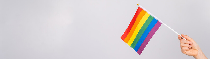 A woman is holding a rainbow flag on a white background.