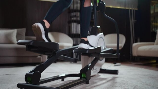 close up female legs running on elliptical orbitrek machine in fitness gym