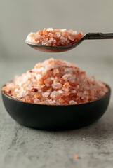 a slide of himalayan pink salt in a wooden bowl and spoon.