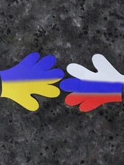 paper palms painted in the colors of the Russian and Ukrainian flags on a black concrete background with copy space