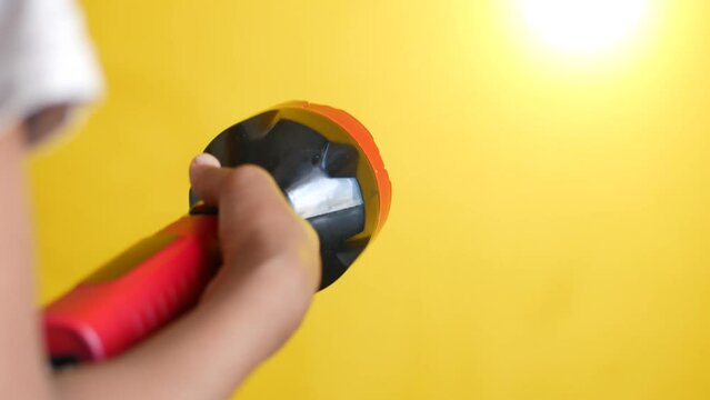 hand holding a tourch light against yellow background,