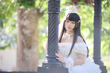 Naklejka premium Beautiful young woman with white lolita dress with european garden Japanese fashion