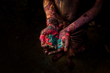 Close-up of the hands of a girl who holds colorful paint while celebrating the festival of color