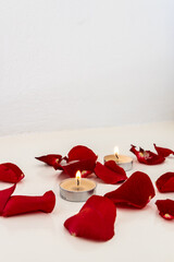 Rose petals and tea lights on a white background