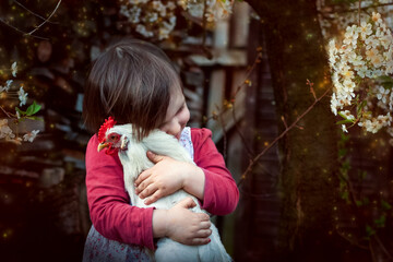 dzieci i zwierzęta - dziewczynka przytula z miłością swoją kurkę - obrazy, fototapety, plakaty