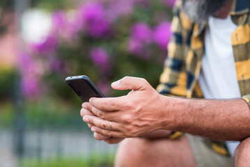Close up of mature man hands typing and writing on a mobile phone. Male hands people using app on smartphone outdoor. Concept of online dating and wireless free connection