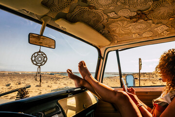 Interior of classic van camper with beautiful legs of woman stretched and relaxed. Travel people lifestyle concept. Summer holiday vacation and vanlife. Dreamcatcher and beach view holiday vacation - Powered by Adobe