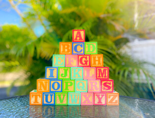 wooden alphabet cubes for kids. cubes on the table and palm tree in the background