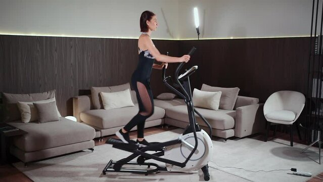 female running on elliptical orbitrek machine in fitness gym or apartment