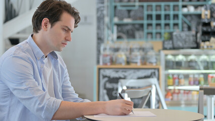Fototapeta na wymiar Pensive Creative Man Writing on Paper, Thinking 