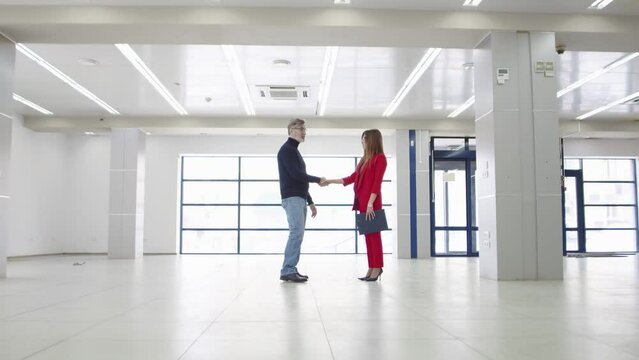 Businessman shakes hands with realtor woman after concluding an office lease deal, front view. Businessman shakes hands with businesswoman after signing contract