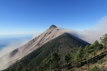 Panorama scene from the breathless Acatenango Volcano in Guatemala in Central America erupting with smoke and lava on a sunny day with a blue sky 
