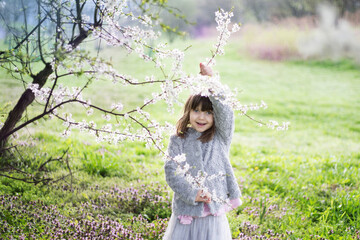 dziewczynka zachwycona wiosną podziwia i wącha kwiaty