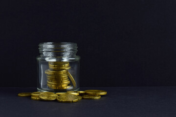 Euro coins scattered and inside a glass jar. Copy space and black background.