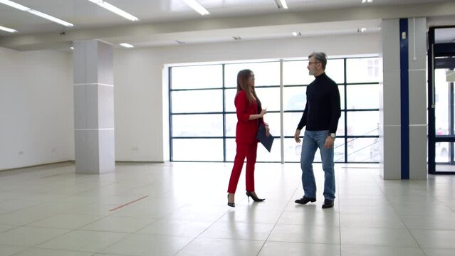 Businesswoman meets with realtor man for business conversation about renting office space, side view. Businesswoman shakes hands with man in spacious room