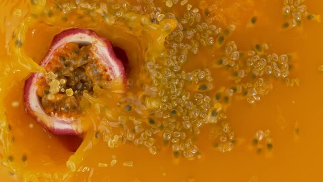Fresh sliced passion fruit falling into juice, super slow motion filmed on high speed cinematic camera at 1000 fps.