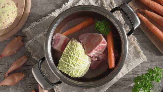 Preparation of broth or soup - putting carrot into a pot with marrow bones, beef meat and vegetables