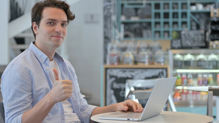 Thumbs Up by Creative Man with Laptop in Cafe 