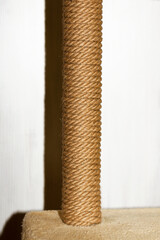 Cat tree and furniture, sisal rope cat scratching post on beige carpet, vertical photo with flash and deep shadows