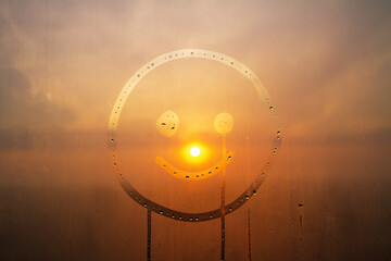 Drawing on wet window, smile wishes you good morning. Positive emoticon on wet window against the sunrise