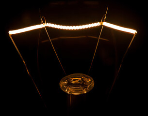 Light bulb closeup illuminated isolated against black background