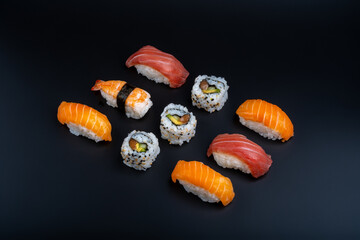 varied sushi ration with black background and props