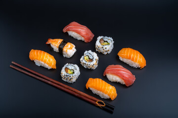 varied sushi ration with black background and props