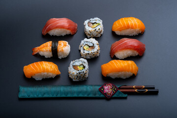 varied sushi ration with black background and props