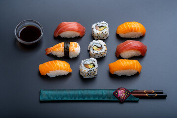 varied sushi ration with black background and props