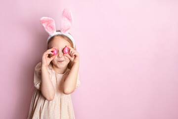 Happy Easter. The cheerful girl hid her eyes behind the colored shiny eggs in her hands. Pink...