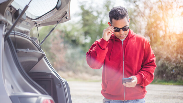 handsome young Hispanic crashed with his car using his cell phone. road safety concept