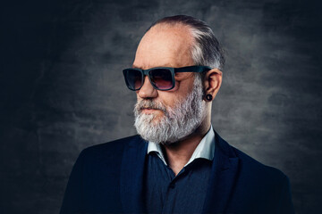 Bearded old man with sunglasses posing against dark background