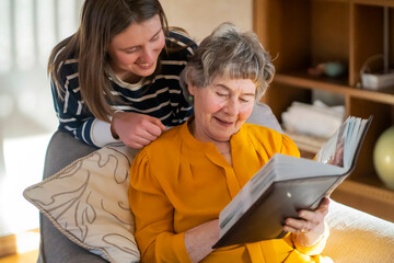 Old woman with her granddaughter look at family photos.