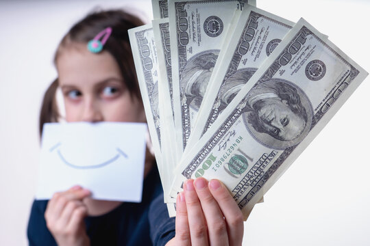 Conceptual image: making money and good business. Beautiful happy young girl holding US Dollar banknotes. Selective focus on money.