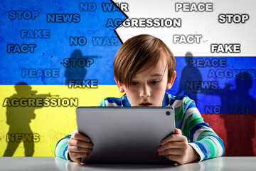 A cute child watches military news in the basement against the background of a wall with...