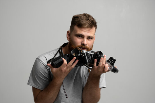 Bearded professional photographer with a bunch of different vintage film cameras in a hands looking on a camera and ready for make a good shoot.