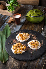 On the serving board is a gourmet dessert green hemisphere with chocolate chips. On a wooden table there is a mug of cappuccino, a sprig of mint in a glass. Close up. Menu for restaurant, cafe, bar.