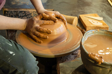 hands of a potter, creating an earthen jar on the circle