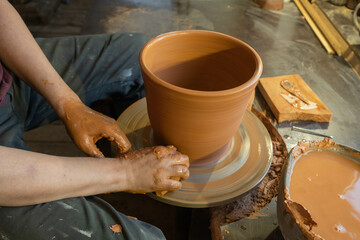 hands of a potter, creating an earthen jar on the circle