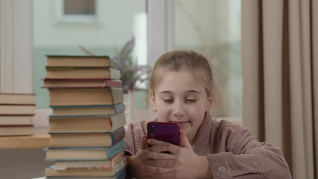girl with a phone in her hands near a stack of books