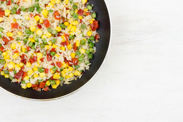 A mixture of rice and vegetables cooked in a frying pan for lunch. Vegetarian food.